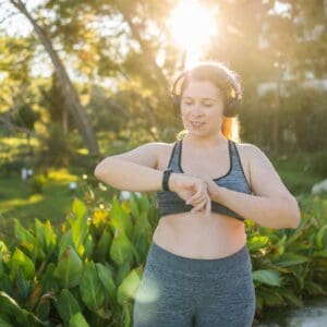 Fat woman checking time or heart rate from smart watch. Exercise or running outdoors for weight loss