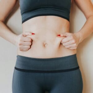 Beautiful young woman showing her imperfect belly after pregnancy. She feeling fat. Women’s health