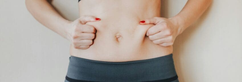 Beautiful young woman showing her imperfect belly after pregnancy. She feeling fat. Women’s health