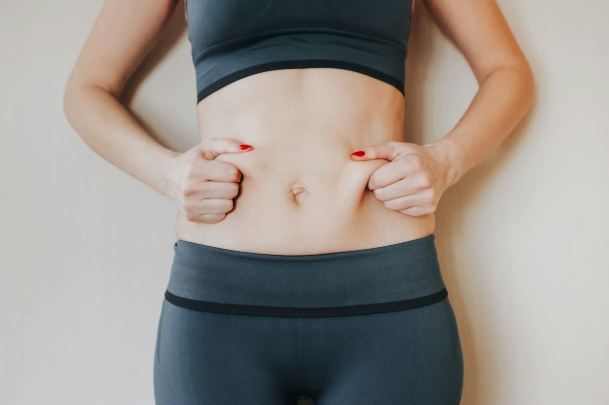 Beautiful young woman showing her imperfect belly after pregnancy. She feeling fat. Women’s health
