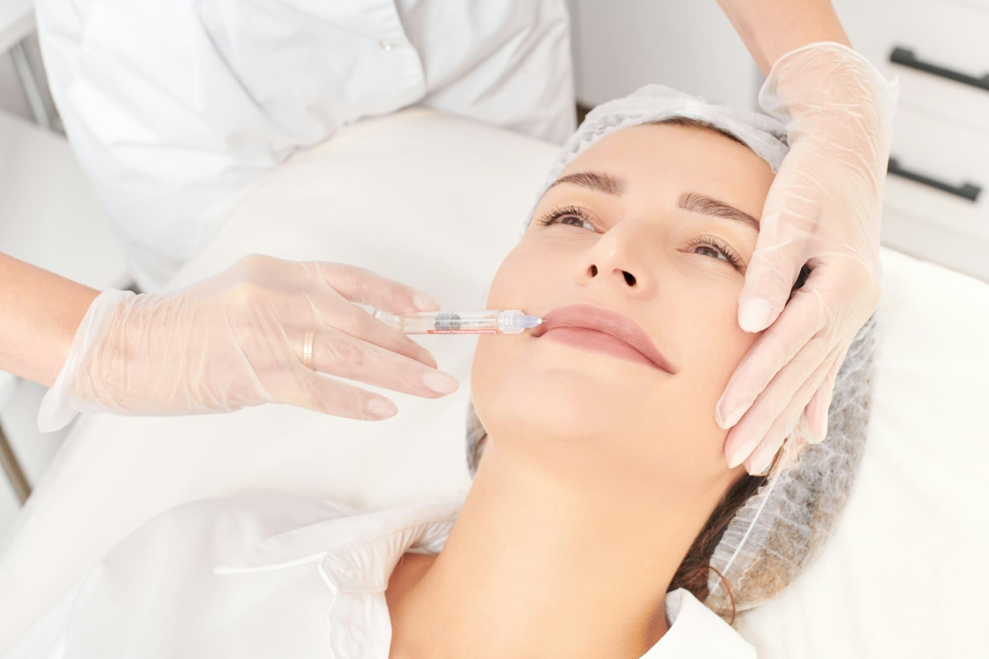 Cosmetologist makes fillers injection for lips augmentation and volume cosmetic procedure