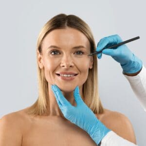 Plastic surgeon drawing lines on middle aged woman face