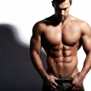 Portrait of young strong man with perfect sportive body posing in studio