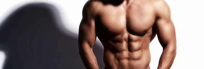 Portrait of young strong man with perfect sportive body posing in studio