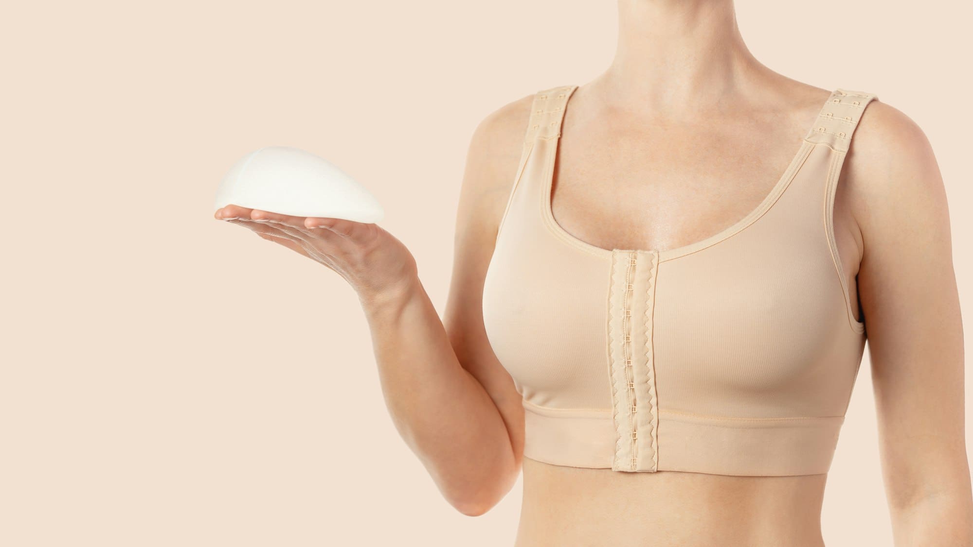 Woman wearing compressing bra after breast augmentation. Anatomical implants