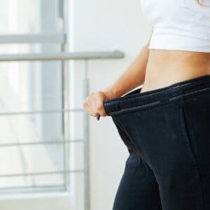 Woman in oversize pants after weight loss, diet concept.