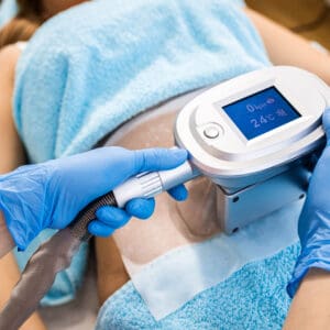 Beautician therapist applying cryolipolysis treatment in beauty salon.