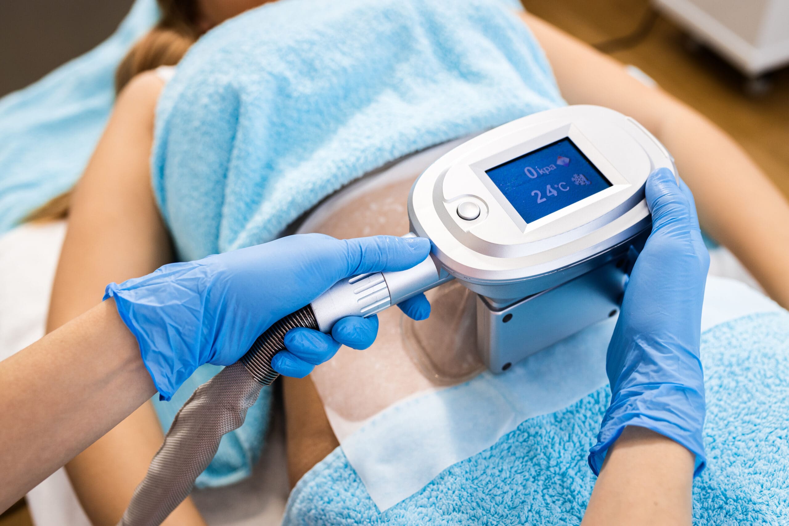 Beautician therapist applying cryolipolysis treatment in beauty salon.
