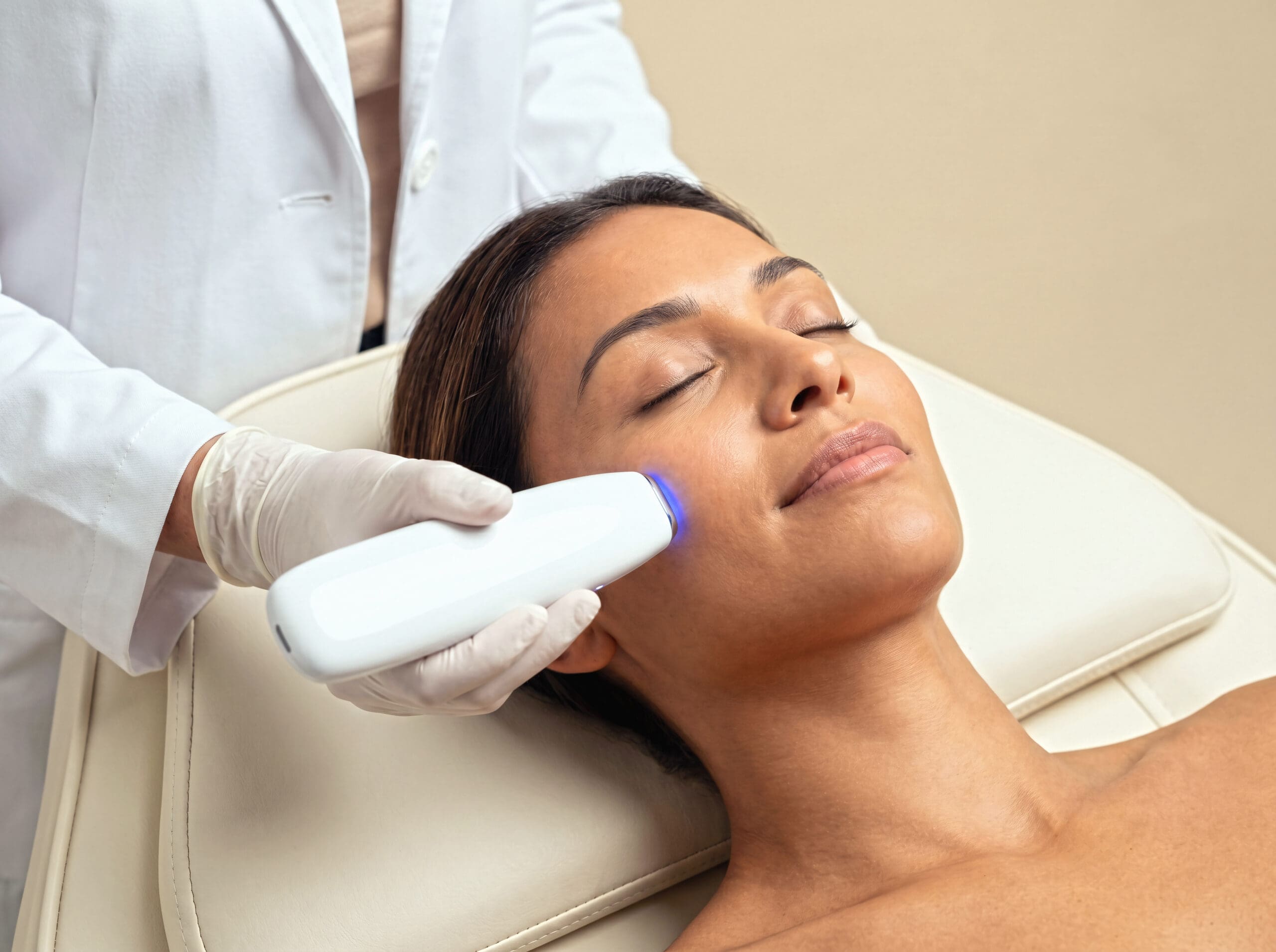 Dermatologist performing cosmetic laser lifting and collagen boost therapy on patient in modern dermatology center